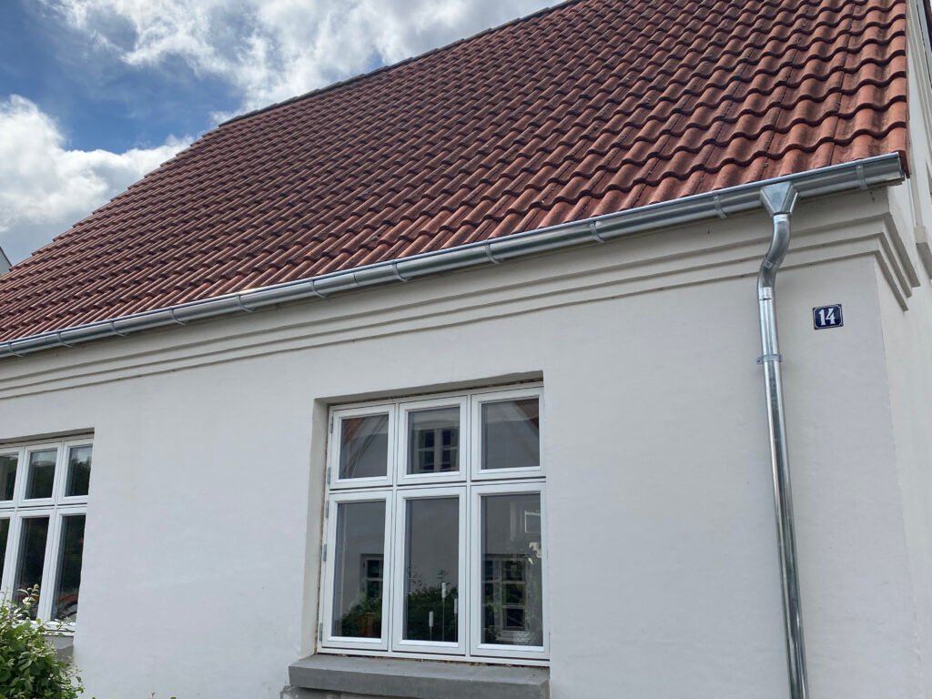 Hvidt hus med rødt tegltag og vinduer